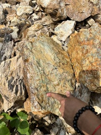 a person is pointing to a rock in a pile of rocks